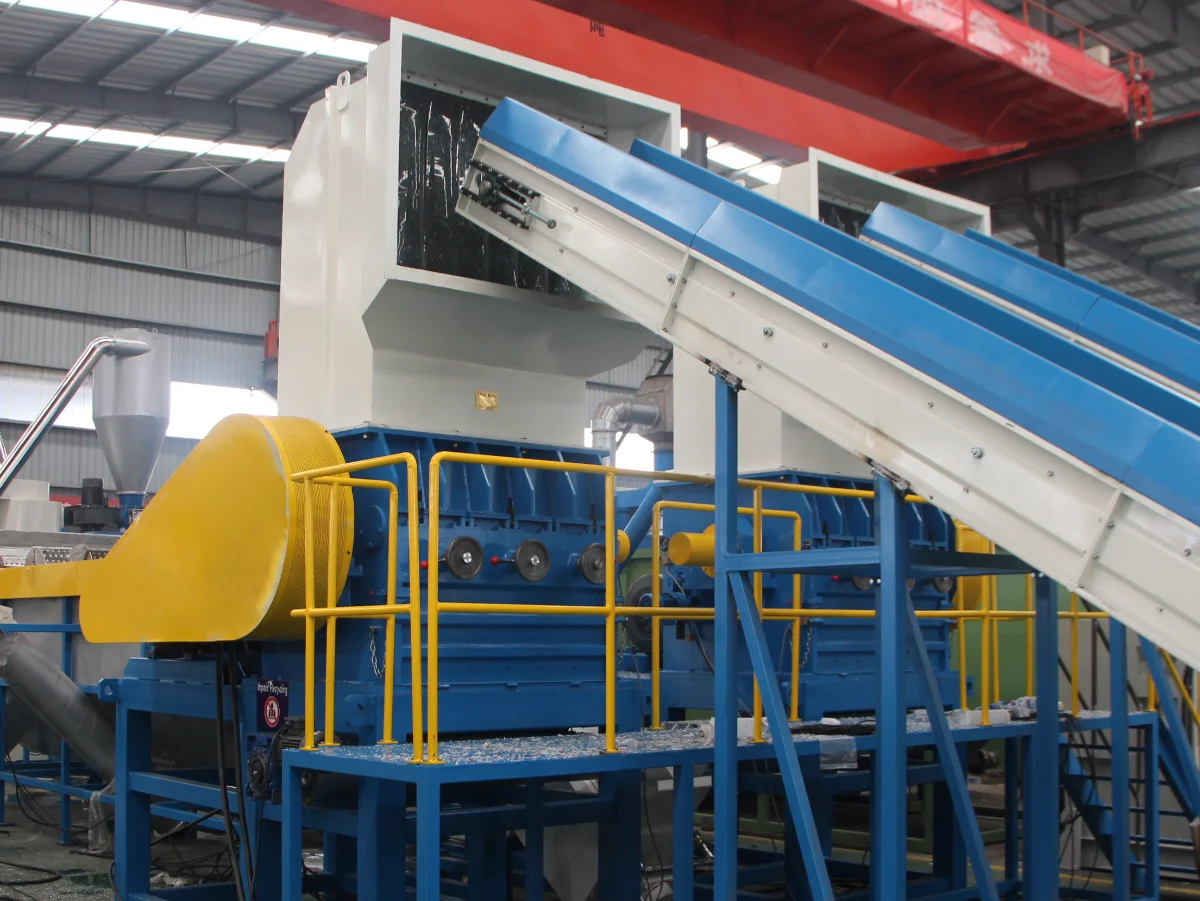 The image depicts a wet plastic grinding machine used in the recycling industry to process plastic waste. This type of machinery combines the steps of washing and grinding plastic materials to prepare them for further processing, such as pelletizing or compounding. The machine includes a large hopper for loading the waste plastic, a water injection system to aid in the breakdown and cleaning of materials, and a conveyor system that transports the plastic through various stages of grinding and washing. The integration of water not only improves the efficiency of the grinding process but also reduces dust and other airborne contaminants, making it an environmentally friendly solution for plastic recycling facilities.