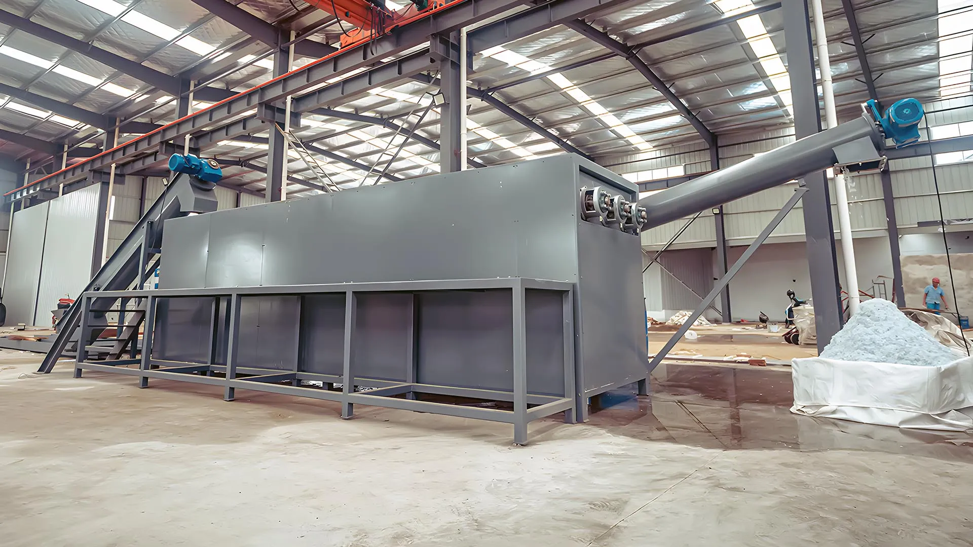 Industrial triple-row sink float separation tank in a recycling facility, showcasing the equipment’s large gray structure with piping and workers managing materials in a spacious warehouse setting