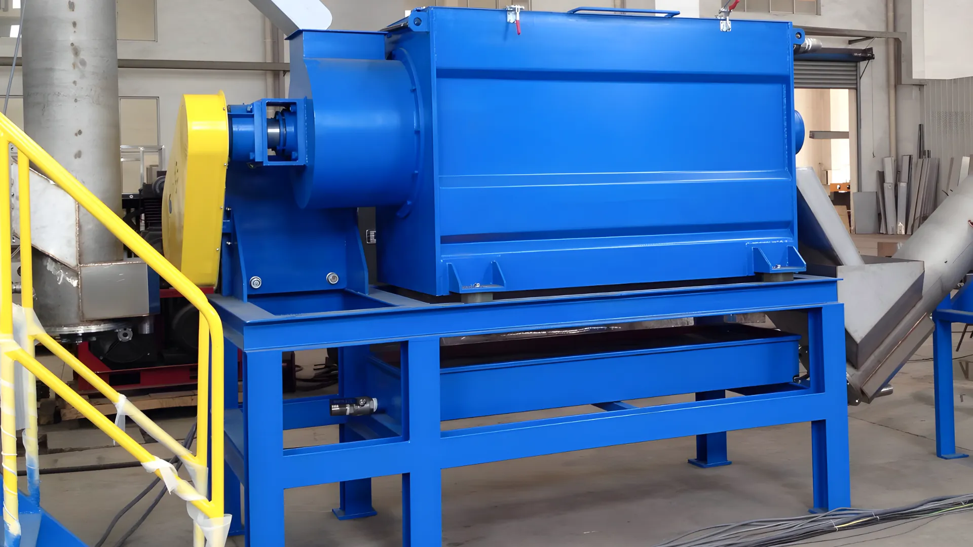 Centrifugal Dryer and Dewatering Machine for Plastic Drying in a factory setting, featuring a bright blue body with a yellow motor and safety railings.