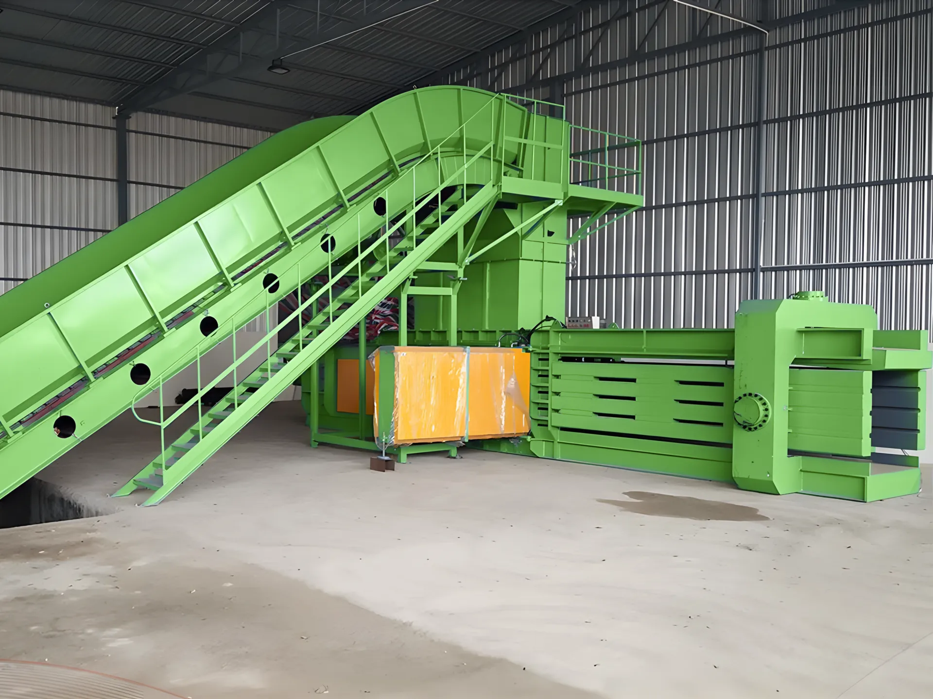 Green horizontal baler with conveyor system in a recycling plant for waste processing.