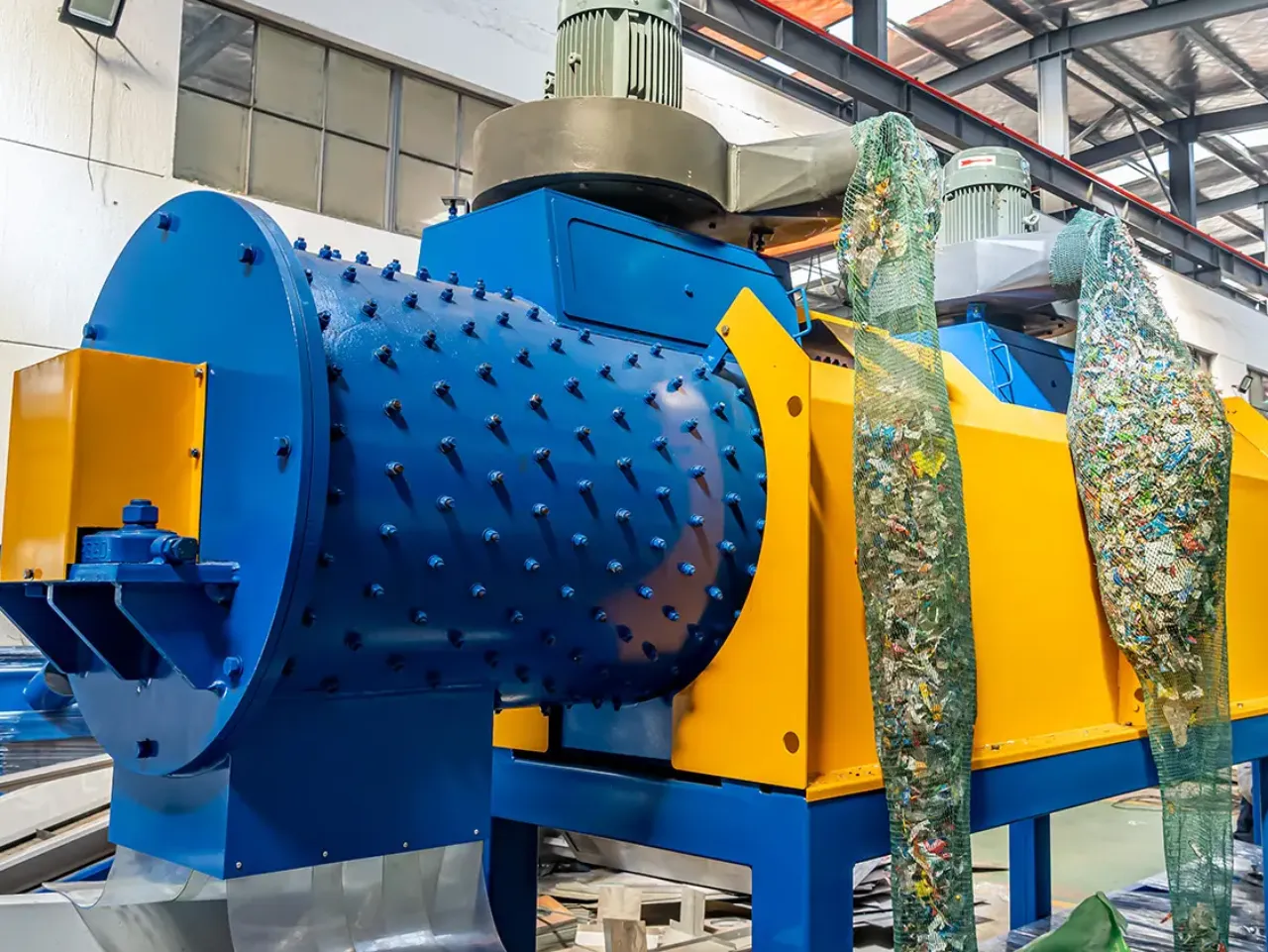 Industriële machine voor het verwijderen van etiketten van plastic flessen in bedrijf bij recyclingbedrijf.