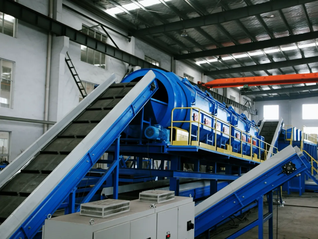 Recycling plant with conveyor belts and rotary drum separator for waste sorting.