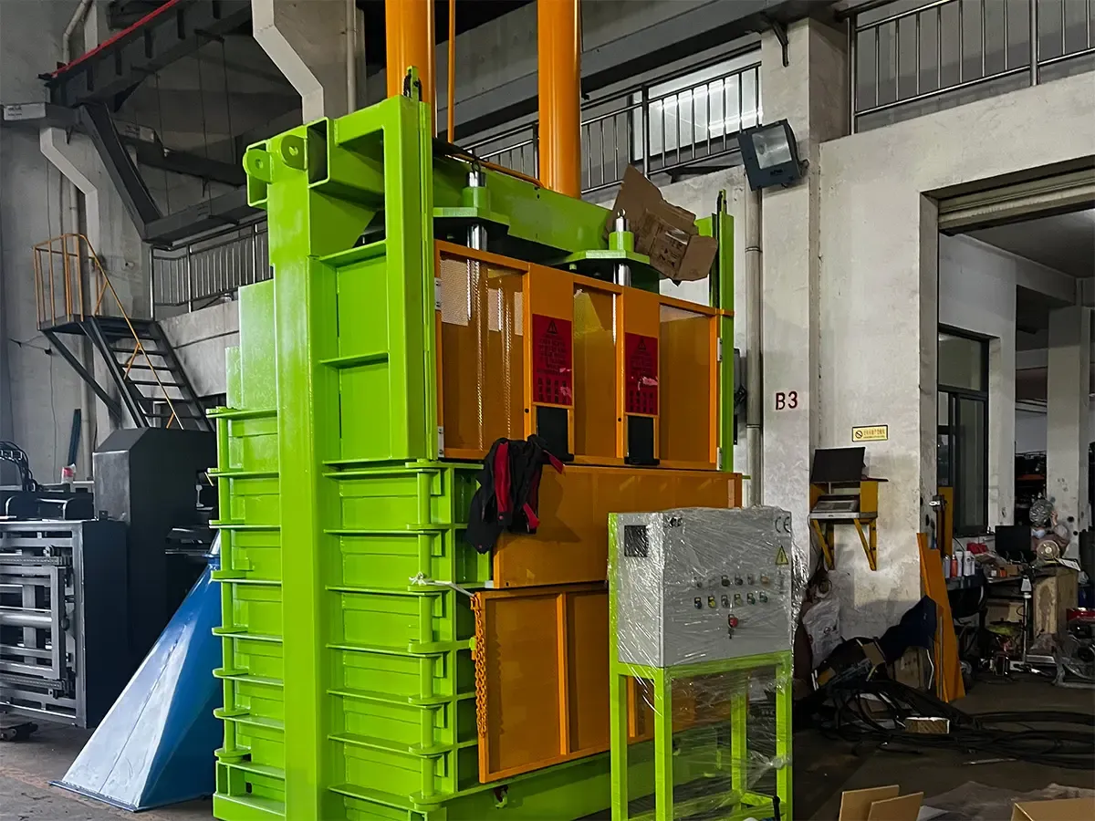 Vertical hydraulic baler in a factory setting for compacting recyclable materials.