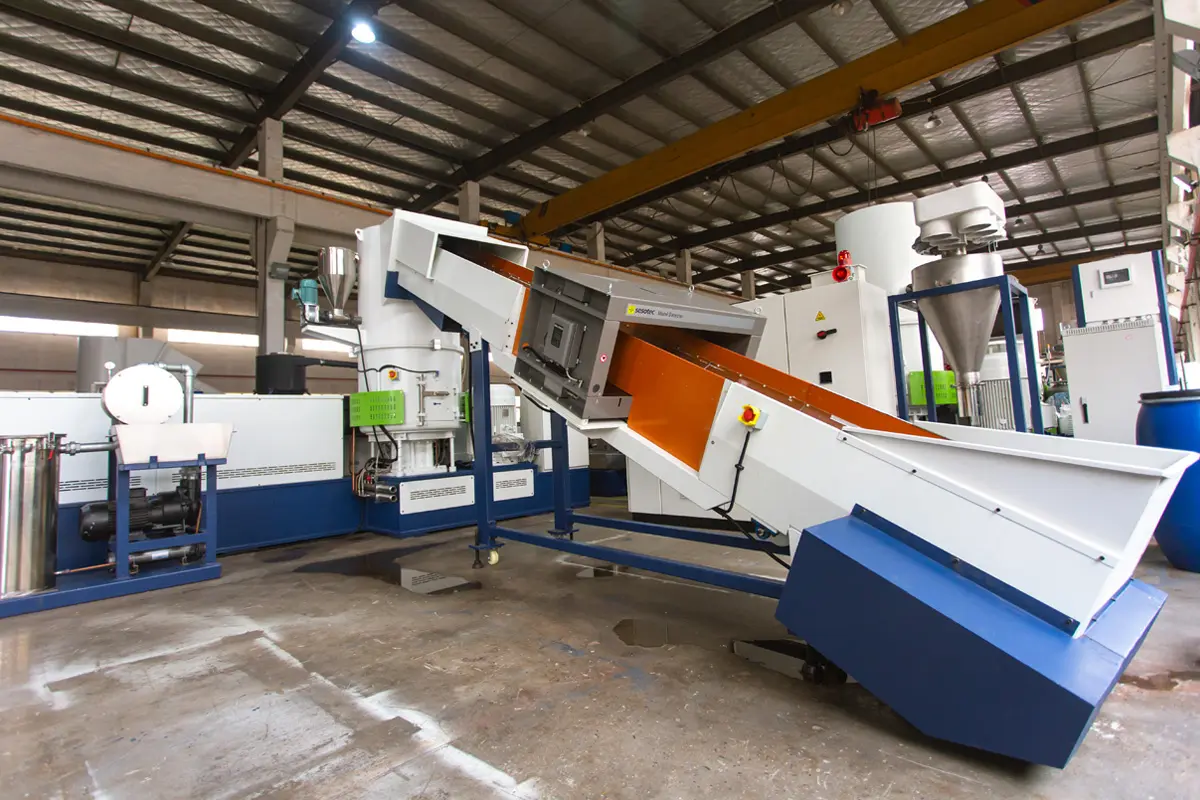 Industrial plastic recycling machine in a factory setting for waste processing.