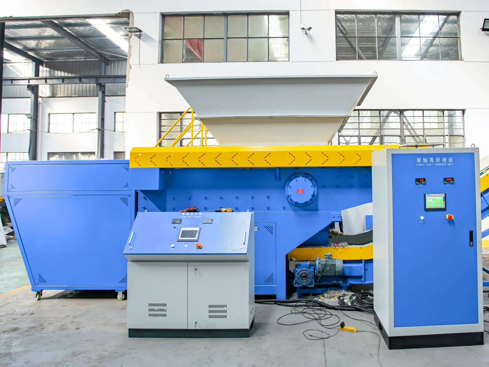 Industrial single-shaft shredder machine in a factory setting for efficient waste processing.